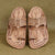 Pair of traditional leather sandals with intricate designs on a textured green background