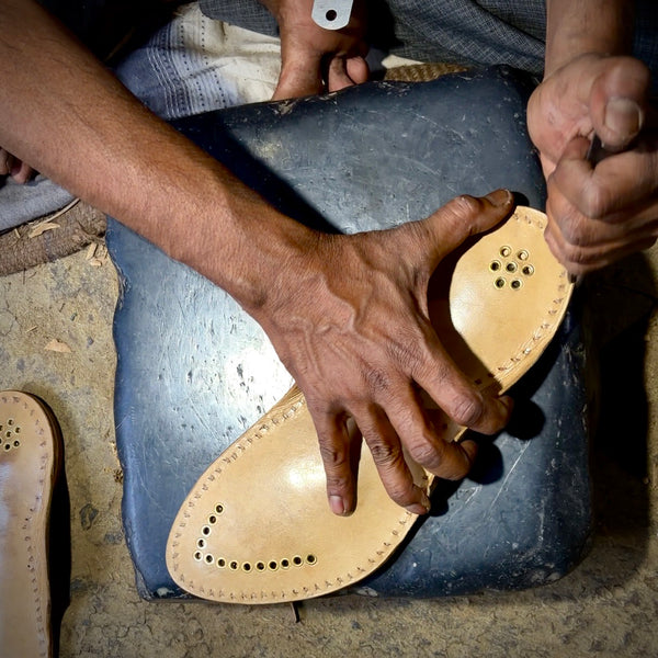 Final polishing and edge finishing by artisan on completed men’s handmade Kolhapuri chappal, ready for authentic tak-tak sound test.