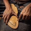 Close-up of premium Kapashi Kolhapuri chappal making for men, artisan detailed hand-stitching thin Veni leather strings onto sound sole base.